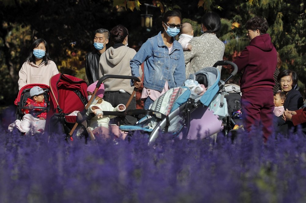 Residents some wearing face masks to help curb the spread of the coronavirus bring their toddlers for sunbathing at a park in Beijing