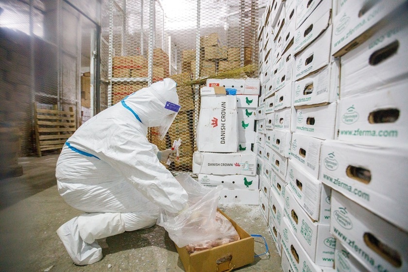 A medical worker prepares to take a frozen chicken from a packing box